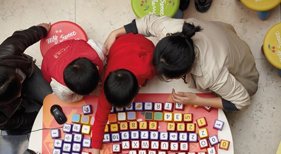 Adults and children playing with alphabet blocks on a table